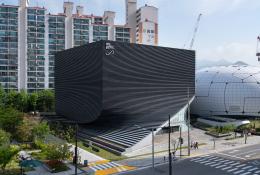 An exterior view of the Photography Seoul Museum of Art (Photo SeMA) features a distinctive twisted silhouette, created using a rhythmic layering of angled precast concrete panels.