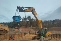 A yellow excavator lifts a blue pile cropper at the Port of Nigg, Scotland