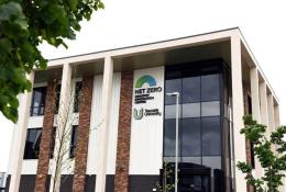 An external view of Teeside University’s Net Zero Industry Innovation Centre (NZIIC), a multi-storey building with a glass, red brick and white render facade.