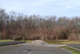 A dead-end road with a pile of illegally dumped concrete hardcore, with trees in the background.