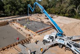 A concrete pump places concrete during construction of foundations