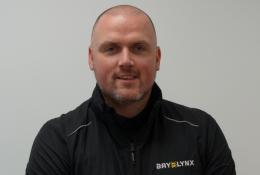 A bald man in a black fleece branded with the Bay-Lynx logo.