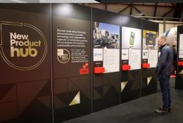 A man stands right of frame looking at entries to the UK Concrete Show's New Product Hub, which are displayed on a large, floor standing board.