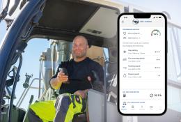 A PPE clad construction worker sits in a machine cab holding a mobile, with a screen shot of the mobile using Kleemann’s SPECTIVE CONNECT app, which now enables remote control and monitoring of crushing and screening equipment, on the right of the picture.