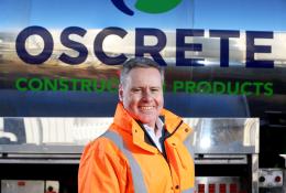 Oscrete director Scott Wilson stand in front of an Oscrete sign wearing orange PPE