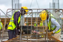 Two men in PPE working on rebar on a construction site