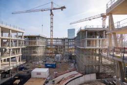 An under construction mid-rise building with two tower cranes in the background