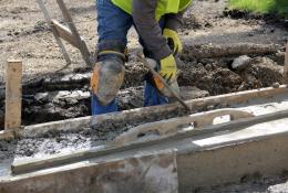 A construction worker using a trowel to help lay concrete foundations