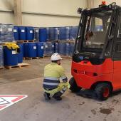 A man in a factory crouching down in front of a forklift