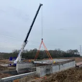 A crane lifting concrete beams to construct a road bridge