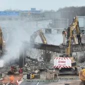A motorway bridge being demolished using several large excavators