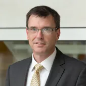 Heasd and shoulders picture of a man in a suit wearing glasses