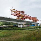 A picture of an orange launching girder sitting on top of an under construction railway viaduct