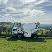 A white mobile concrete mixer in a green field