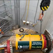 A yellow TBM being lowered into a launch pit