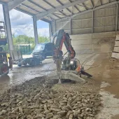 A demolition robot using a hammer to break a concrete floor