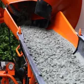 A close up of an orange cement mixer's chute discharging concrete