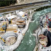 A large construction site divided by a bend in a river