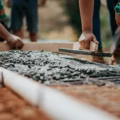 Men spreading wet concrete in a mesh mould