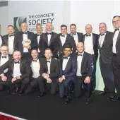 Lots of men in a line wearing black tie celebrate winning the Concrete Society’s annual Awards for Excellence in Concrete 2024 at The Royal Lancaster London