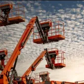 Orange aerial work platforms set against a backdrop of white, fluffy clouds