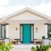 A white, single storey house with a green door