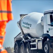 A man in orange PPE and a Heidelberg Materials concrete truck mixer