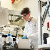 A man in lab coat and safety goggles working in a laboratory.