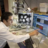 A man in lab clothes looking at monitors in a laboratory