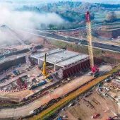 An aerial view of the A46 Kenilworth Bypass box structure under construction with a large yellow and red crawler crane and a smaller white telescopic crane and white crawler crane. Image: HS2.