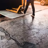 A man using a yellow trolly to unload a lorry onto a loading dock