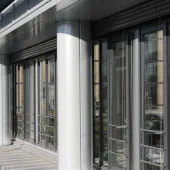 A glass fronted office with concrete columns.