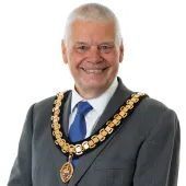 A photo of Paul Gandy, president, CIOB, wearing a grey suit, white shirt, blue tie and ceremonial chain.