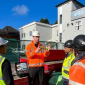 Men in a variety of PPE in front of a dental surgery discuss PERI UK and SWS's integrated waterproofing and formwork solution