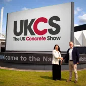 Richard Bradbury (right), Managing Director of The QMJ Group with Helaena Ackers, Exhibition Sales Account Manager, The NEC shake hands outside the NEC in front of a huge UK Concrete Show sign, following the signing of a two-year deal that sees the flagship trade show to stay at Birmingham’s NEC through 2027, with free parking and expanded plans for 2026 edition