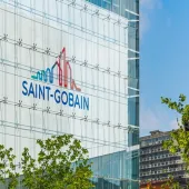 The blue and red Saint-Gobain logo on the side of a glass paneled, high-rise building.