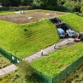 An aerial photo shows men in PPE and two vans at Stanley Hollowhouse following the installation of the cement-free, basalt-reinforced base for Scottish Water’s first verified Net Zero site.