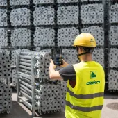 A man in Doka branded PPE uses an AI device to count formwork elements