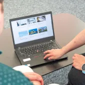 Two people look at a laptop screen which shows several photos and text related to sustainable construction
