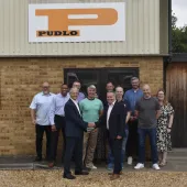 Malcolm Thornton and Scott Wilson (shaking hands) pictured with the PUDLO team outside their office following the deal to buy the company.