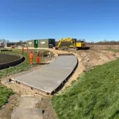 A waste water treatment plant with a CoMLaG mix access road in the foreground surrounded by grassy banks