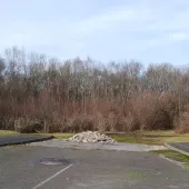 A dead-end road with a pile of illegally dumped concrete hardcore, with trees in the background.