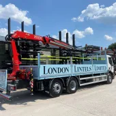A blue London Lintels liveried truck with red loader crane mounted at the rear in London Lintels yard. London Lintels, now part of the Milbank Group, distributes concrete and steel lintels to customers across London and the South.