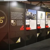 A man stands right of frame looking at entries to the UK Concrete Show's New Product Hub, which are displayed on a large, floor standing board.