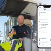 A PPE clad construction worker sits in a machine cab holding a mobile, with a screen shot of the mobile using Kleemann’s SPECTIVE CONNECT app, which now enables remote control and monitoring of crushing and screening equipment, on the right of the picture.