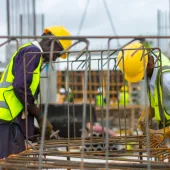 Two men in PPE working on rebar on a construction site