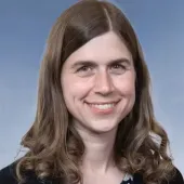 A close-up shot of a smiling Julie Holmquist, marketing content writer, Cortec Corporation, wearing a black top with floral pattern