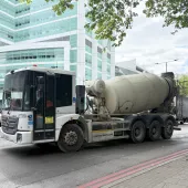 A concrete mixer drives along a street in London with a red double decker following 