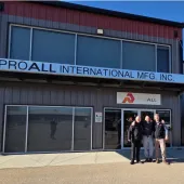 Three men stand awith hands on each other's shoulders outside a two storey, ProAll branded building