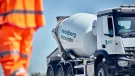A man in orange PPE and a Heidelberg Materials concrete truck mixer